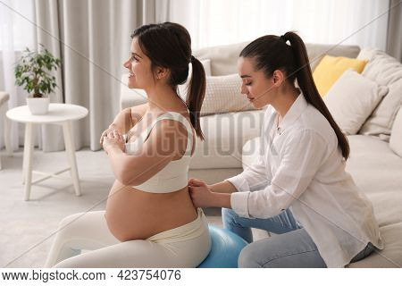 Doula Working With Pregnant Woman In Living Room. Preparation For Child Birth