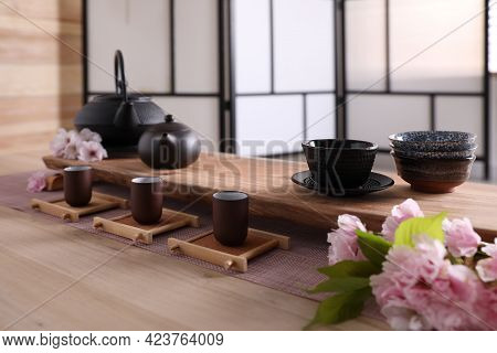 Beautiful Set For Traditional Tea Ceremony And Sakura Flowers On Wooden Table