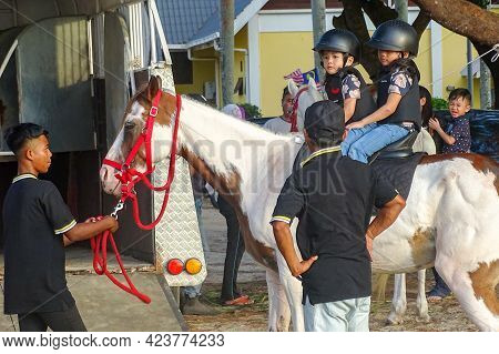 Labuan,malaysia-sept 1,2019:children In Helmet Sitting On Horse And Riding Together Outdoor Park At 