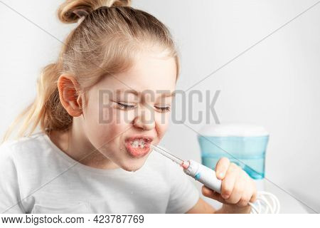 Water Flosser. Little Girl Child Brushes Teeth. Water Jet From The Irrigator.