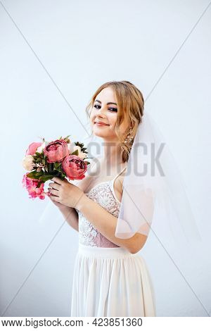 Brunette Girl In A Wedding Dress. Bride In A White Dress With A Bouquet In Her Hands. Makeup.
