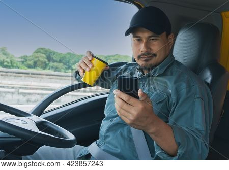Truck Driver Video Call On Smartphone In Cockpit. Trucker Asian Young Man Beard Parked For Coffee Br