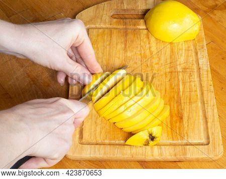Hands Cut With A Sharp Knife Yellow Iva Into Thin Pieces On A Wooden Kitchen Board.
