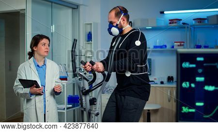 Performance Athlete Talking With Medical Researcher Running On On Cross Trainer In Sports Science La