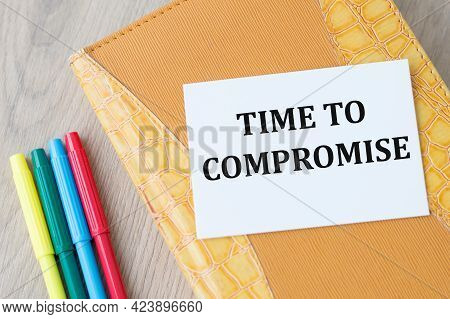 Time To Compromise Text On A White Card That Lies On A Closed Notebook Against A Wooden Background