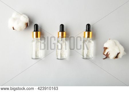 Serum Or Oil Bottle With Pipette And Cotton Twig On Grey Background. Beauty Product, Skin Care Conce