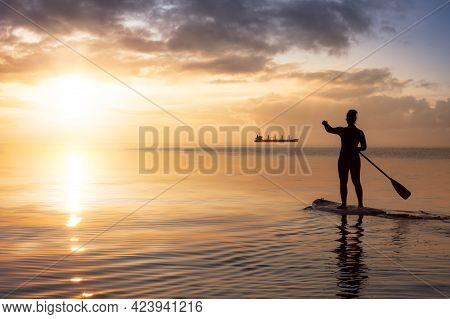 Adventurous Woman On A Paddle Board Is Paddeling In The Pacific West Coast Ocean. Sunset Sky Art Ren