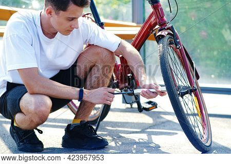 Pumping Air Into An Empty Bicycle Wheel. A Man Shakes A Bicycle Wheel In A Park. A Person Inflates A