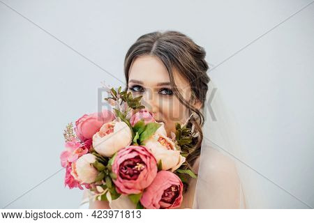 Brunette Girl In A Wedding Dress. Bride In A White Dress With A Bouquet In Her Hands. Makeup.