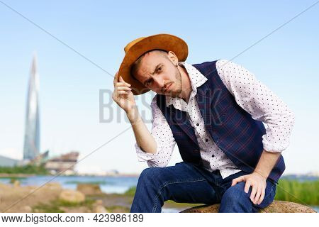 Close Up Portrait Of Handsome Stylish Casual Man Traveler In Hat Sitting At Sea Coastline And Enjoyi