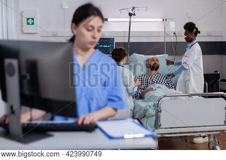 Front View Of Asisstant Typing Medical Expertise On Computer While In Background Black Practitioner 