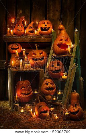 Scary Jack O Lantern Halloween pumpkins against wooden wall in darkness