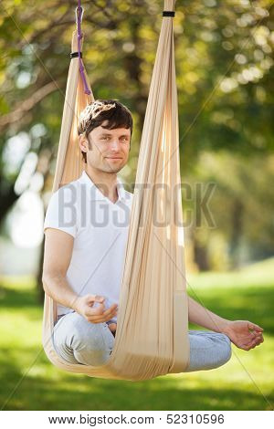 Anti-gravity Yoga, man doing yoga exercises in the park