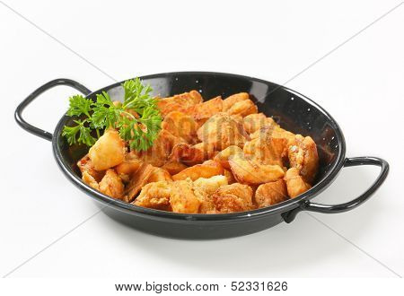 portion of fried pork greaves in an iron pan