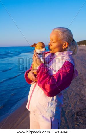 Ung kvinde med hendes hund på en strand