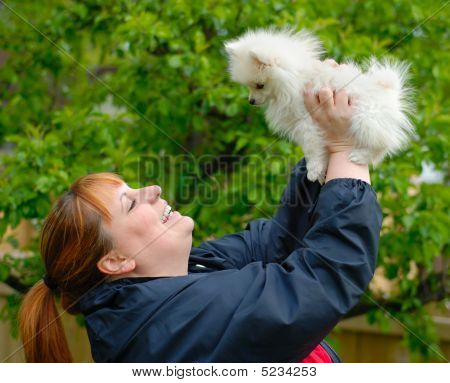Femme souriante tenant un Adorable chiot Pomeranian blanc