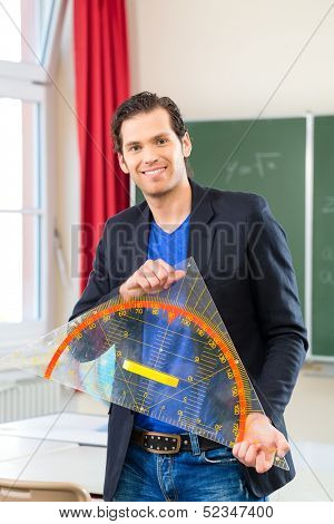 Teacher or docent in school holding a geometry triangle in front of a blackboard in school class 