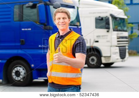 Logistics - proud driver or forwarder in front of trucks and trailers, on a transshipment point