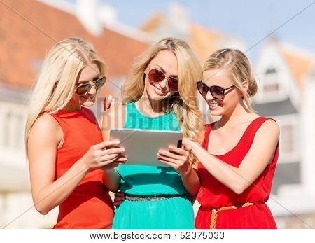 holidays and tourism concept - beautiful blonde girls toursits looking into tablet pc in the city