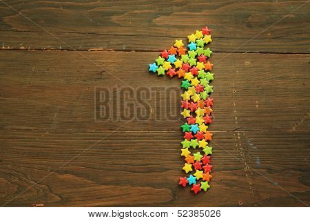 Number one made with star shape candies on a wooden table