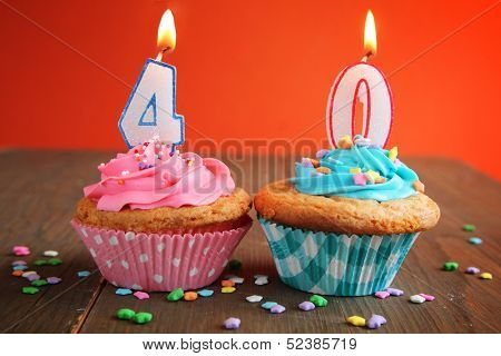 Number forty birthday candles on a blue and pink cupcake on a orange background