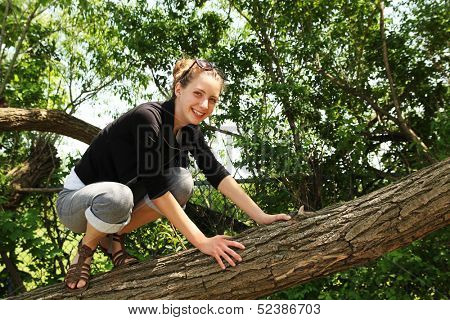 Smiling teenager climbing in a tree by a nice summer day