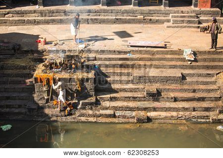 KATHMANDU, NEPAL - DEC 3, 2013: Unidentified local people during the cremation ceremony along the holy Bagmati River in Bhasmeshvar Ghat at Pashupatinath temple in Kathmandu.