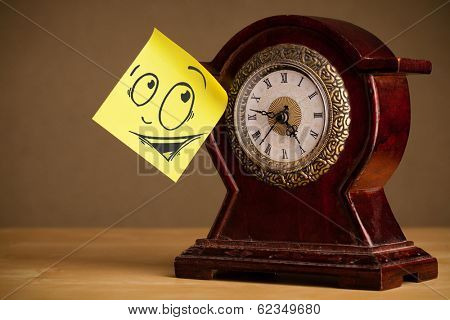 Drawn smiley face on a post-it note sticked on alarm clock
