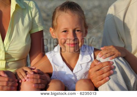 Smiliing Tochter sitzt zwischen Parentson Strand