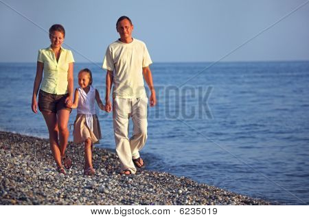 Familie mit Mädchen Spaziergänge entlang sunset Meerstrand