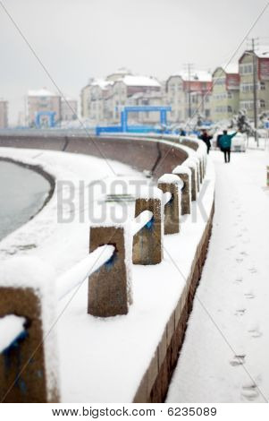 Bílý sníh části zábradlí u moře
