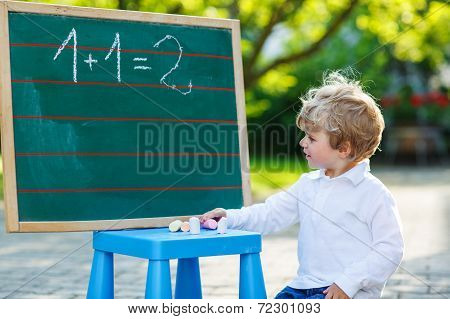 Little Boy At Blackboard Practicing Mathematics