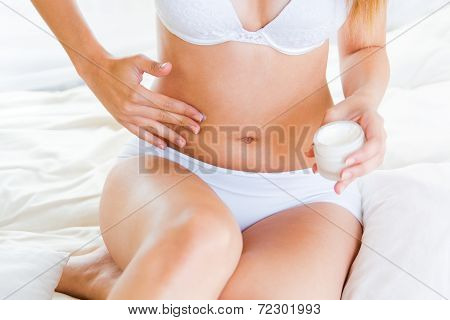Young Woman Applying Skin Moisturizer Abdomen. Isolated On White.