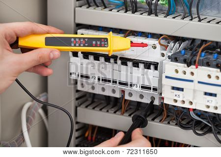 Electrician Examining Fusebox With Voltage Tester