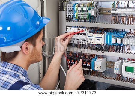 Technician Examining Fusebox With Multimeter Probe