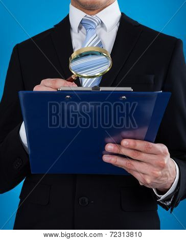 Businessman Examining Document With Magnifying Glass