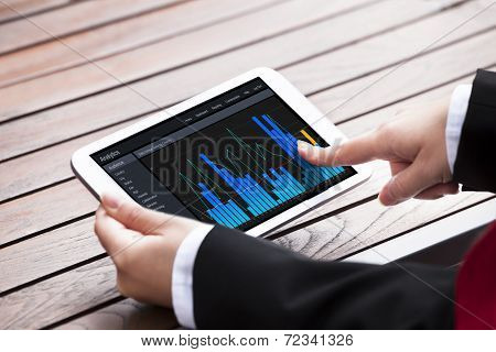 Businesswoman Analyzing Bargraphs On Digital Tablet