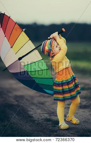 little girl with rainbow umrella in the field
