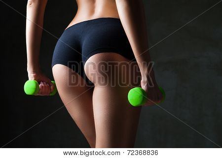 Body of young fit woman lifting dumbbells