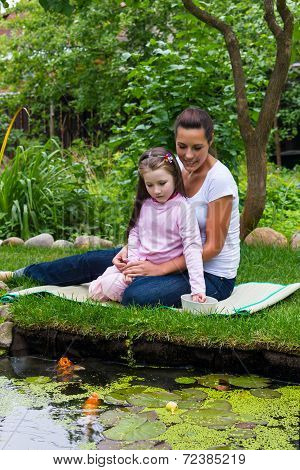 Little Girl With Mum Feeding Fishes