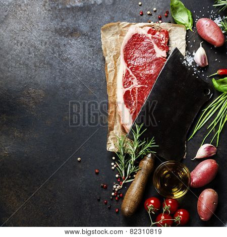 vintage cleaver and raw beef steak on dark background