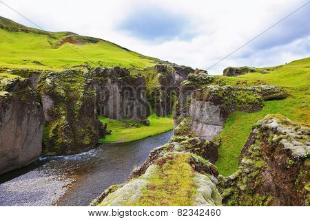 Iceland in July. Canyon Fjadrargljufur and cold fast river with a pebble bottom