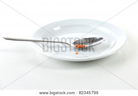 Remnants of lentils n spoon on plate with spoon isolated on white