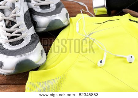 Sport shoes and clothes on wooden background