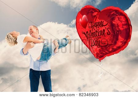 Mature man carrying his laughing partner against blue sky with clouds