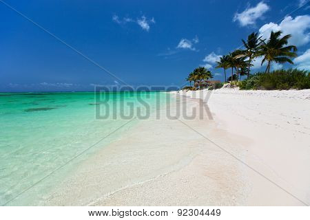 Beautiful tropical beach with palm trees, white sand, turquoise ocean water and blue sky at Anegada, British Virgin Islands in Caribbean