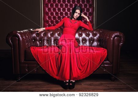young woman in red dress sitting on leather sofa