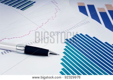 Pen resting on sheets of paper with graphics