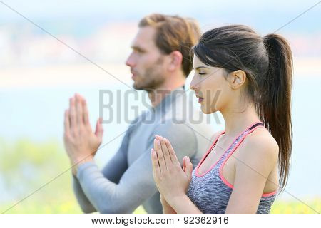 Couple doing meditation and yoga exercises in outdoor park