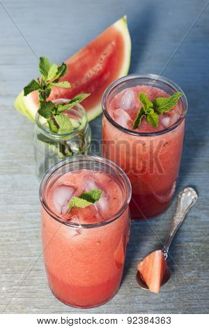 Fresh watermelon slush frozen drinks in two glasses on blue rustic wooden background